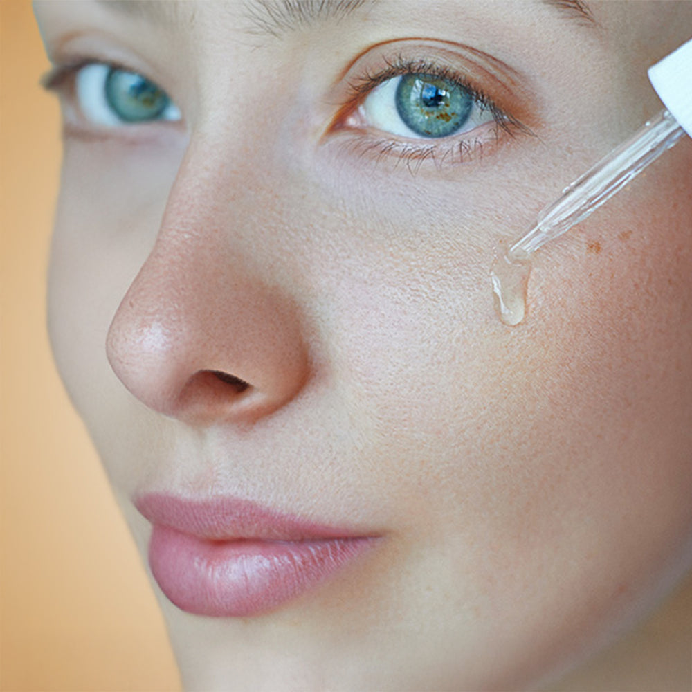 Woman applying a facial serum with a dropper as part of a Korean skincare routine