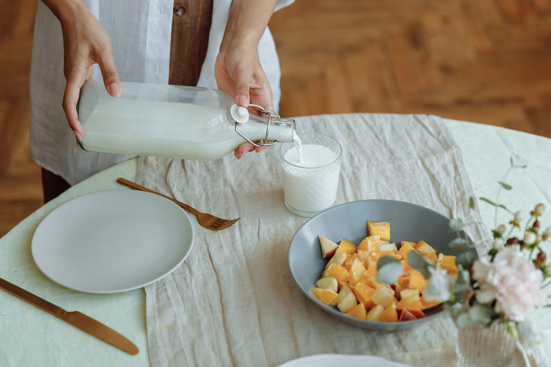Milk being poured into a glass at a breakfast table
